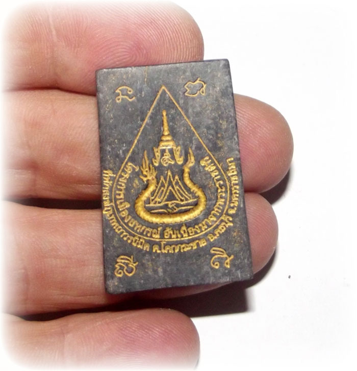 rear face of Pra Somdej Paya Ngiw Dam amulet in hand for size comparison